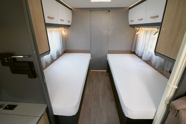 Das mittels Holzschiebetür und Faltvorhang abteilbare Schlafzimmer glänzt mit grossen Einzelbetten, deren hochwertige Matratzen für erholsame Nachtruhe sorgen.