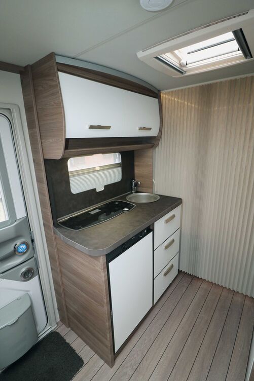 Die kompakte Küche mit den hellen Fronten gefällt, und durch die nach hinten versetzten Einbauten von Herd und Spüle bleibt noch ausreichend Arbeitsfläche.