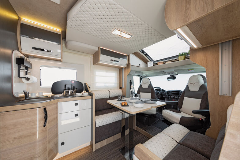 Polster aus gestepptem Leder und Stoff auf Chrom verzierten Oberflächen, hochglänzende Fronten in Weiss an den Oberschränken, kombiniert mit mattem Holz am Möbelkorpus.