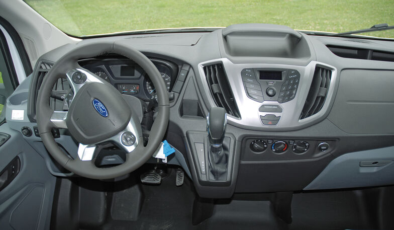 Übersichtliches Fahrerhaus mit Lederlenkrad und -schalthebel.