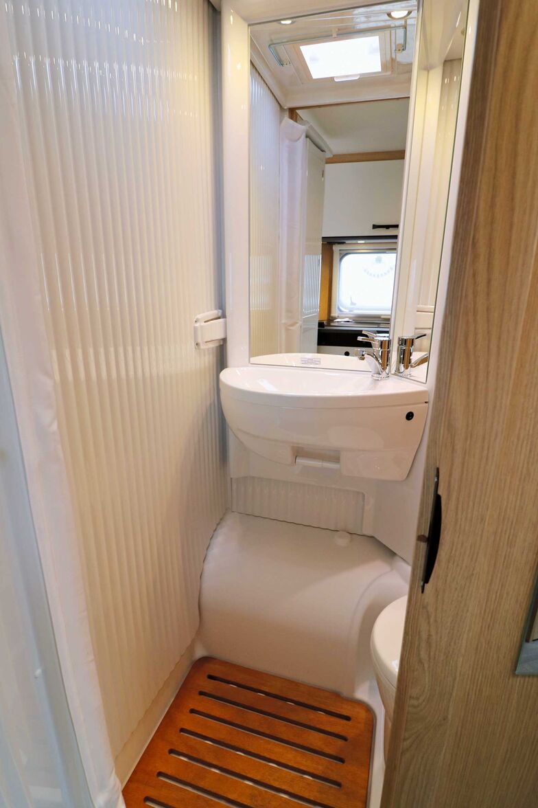 Im Bad lässt sich das Wandelement über dem Radkasten mit dem Wasch­becken zur Seite schwenken. So entsteht ein spritzwasser­geschützter Duschbereich.