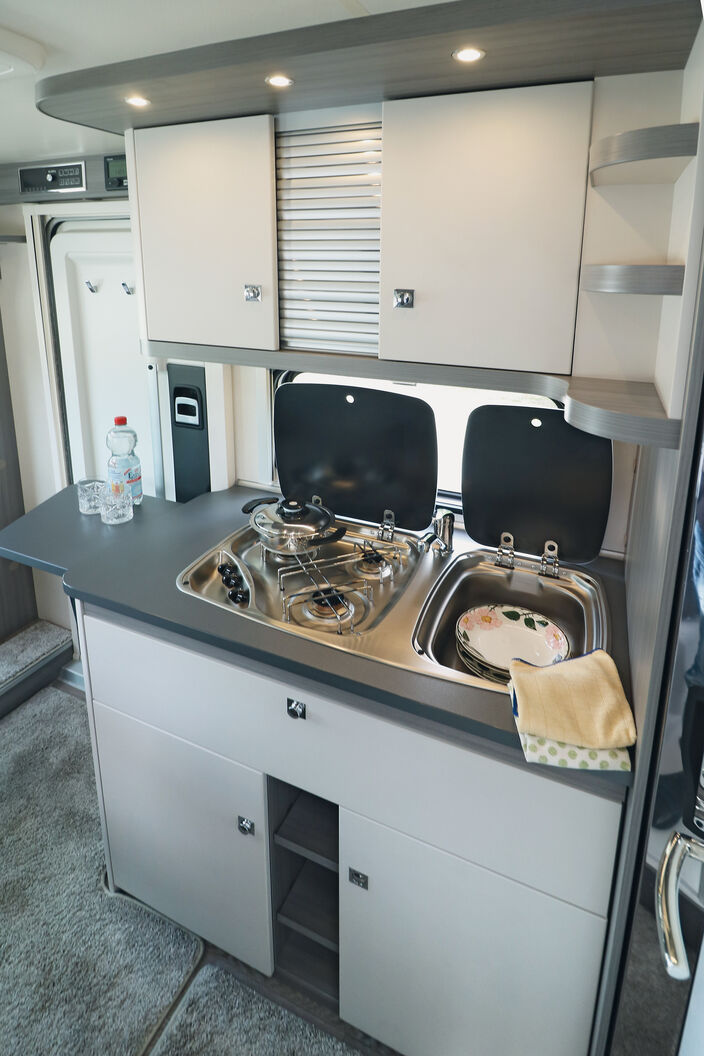 Mit den hellen Fronten und den dunkelfarbigen Elementen, beleuchtetem Baldachin, Ablagen und Stauräumen gefällt die Küche auf Anhieb.