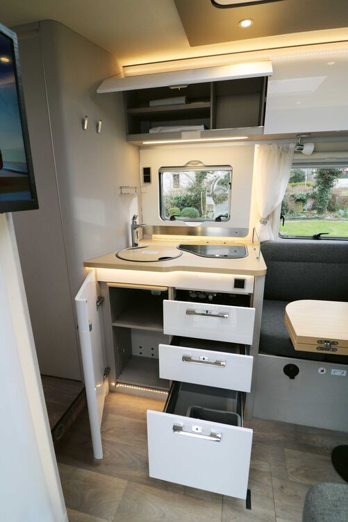 Die kompakte Küche mit ihren hell glänzenden Fronten, holzfarbiger Arbeitsplatte und vielfältiger Beleuchtung kann ebenso punkten wie die Ausstattung.