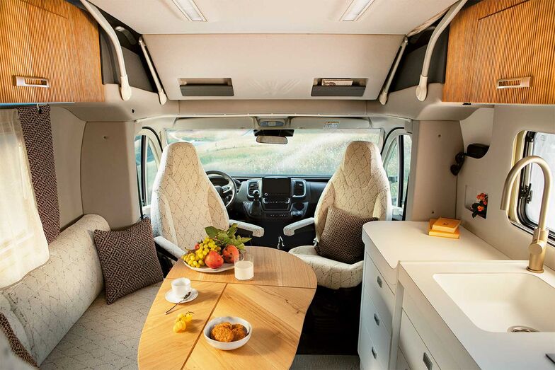 Wohnlich trotz Kompaktmass: der Wohnraum des Oasi 540.1 mit L-förmiger Sitzecke, drehbaren Cockpit-Sitzen, verschiebbarem Tisch und Küchenzeile.
